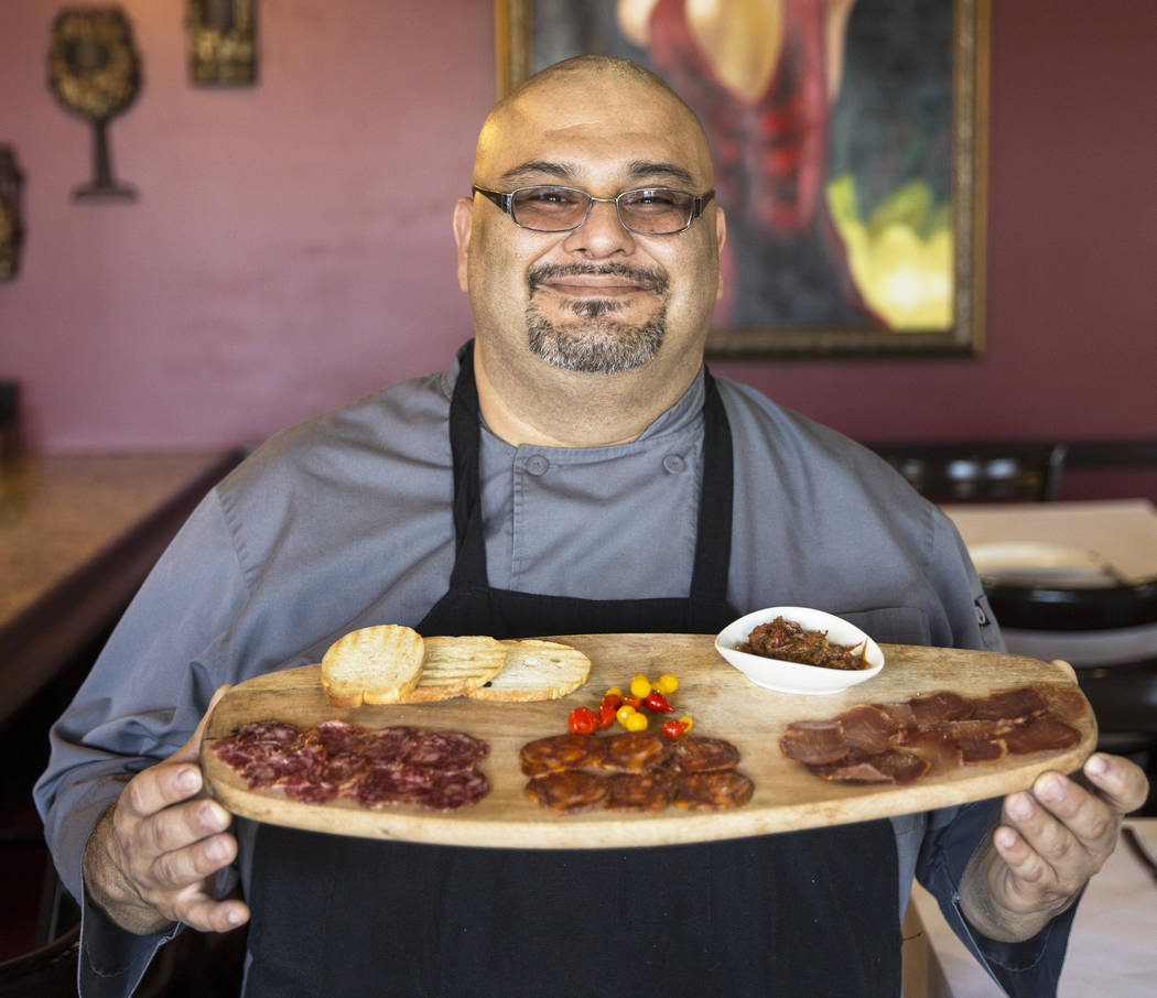 Executive chef Ariel Zuniga holds salchichon, acorn fed iberico salami, chorizo iberico, dry ib ...