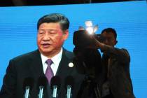 A cameraman films near a screen live broadcasting Chinese President Xi Jinping opening the Seco ...