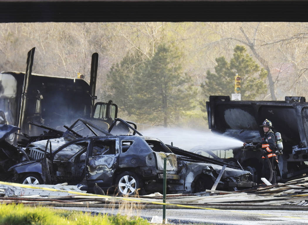 A firefighter sprays water on the wreckage in Lakewood, Colo., after a deadly collision on Inte ...