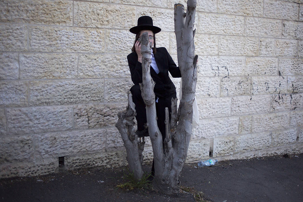 An Ultra-Orthodox Jew watches the funeral procession of Rabbi of the Kaliv Hasidic dynasty and ...