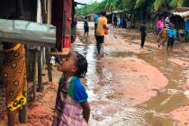 A child drinks water from a gutter during floods due to heavy rains in Pemba, Mozambique, Sunda ...