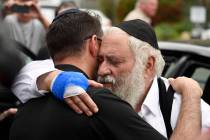 Rabbi Yisroel Goldstein, right, is hugged as he leaves a news conference at the Chabad of Poway ...