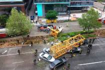 Fire and police crew members work to clear the scene where a construction crane fell from a bui ...