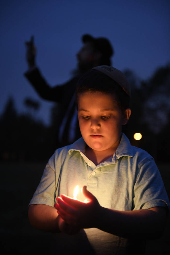 A boy holds a candle during a vigil held for victims of the Chabad of Poway synagogue shooting, ...