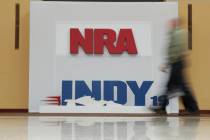 A visitor to the at the National Rifle Association Annual Meeting walks past signage for the ev ...