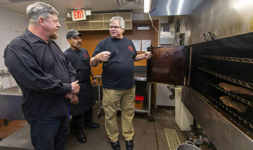 New employee Ron Cochran receives some smoker training from kitchen manager Alvaro Hernandez an ...
