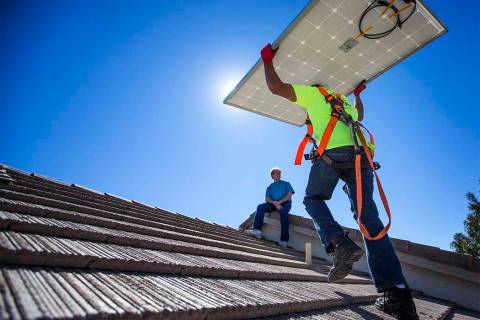 Matt Neifeld with Robco Electric carries a solar panel at a home in northwest Las Vegas on Frid ...