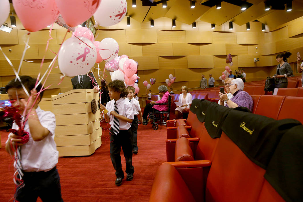 Kindergarteners from The Meadows School, Justin, Nicolas, and Owen, present balloons ...