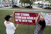 Volunteers hang banners around the perimeter of Marjory Stoneman High School in Parkland, Fla., ...