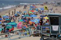 In this July 8, 2017 file photo a lifeguard scans a crowded shoreline at Manhattan Beach, Calif ...