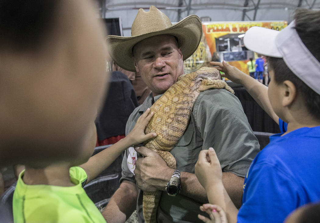 Brian Cheek, middle, an exotic animal handler, holds a savannah monitor while kids pet the liza ...