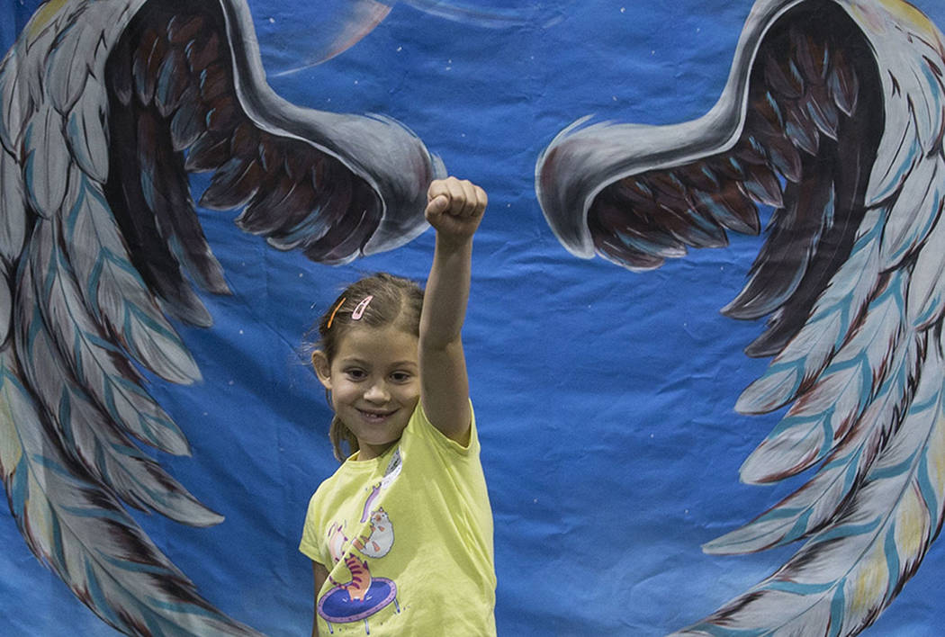 Amber Marica, 7, takes a photo in front of a trick art mural by family activity center HeadzUP ...