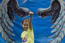 Amber Marica, 7, takes a photo in front of a trick art mural by family activity center HeadzUP ...