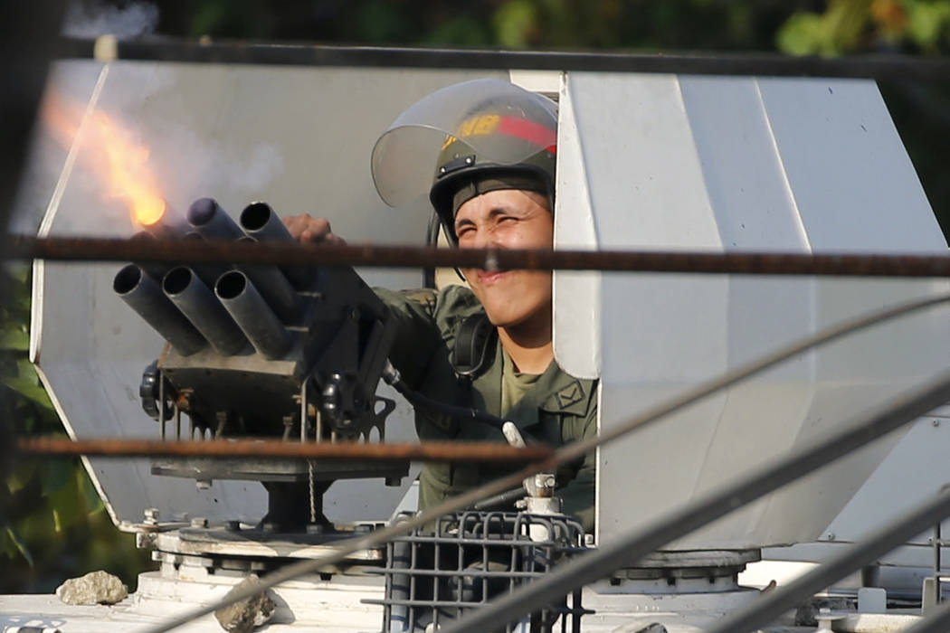 A Bolivarian National Guard loyal to Venezuela's President Nicolas Maduro fires tear gas from i ...