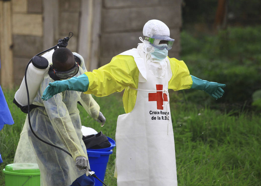 A health worker sprays disinfectant on his colleague after working Sept. 9, 2018, at an Ebola t ...