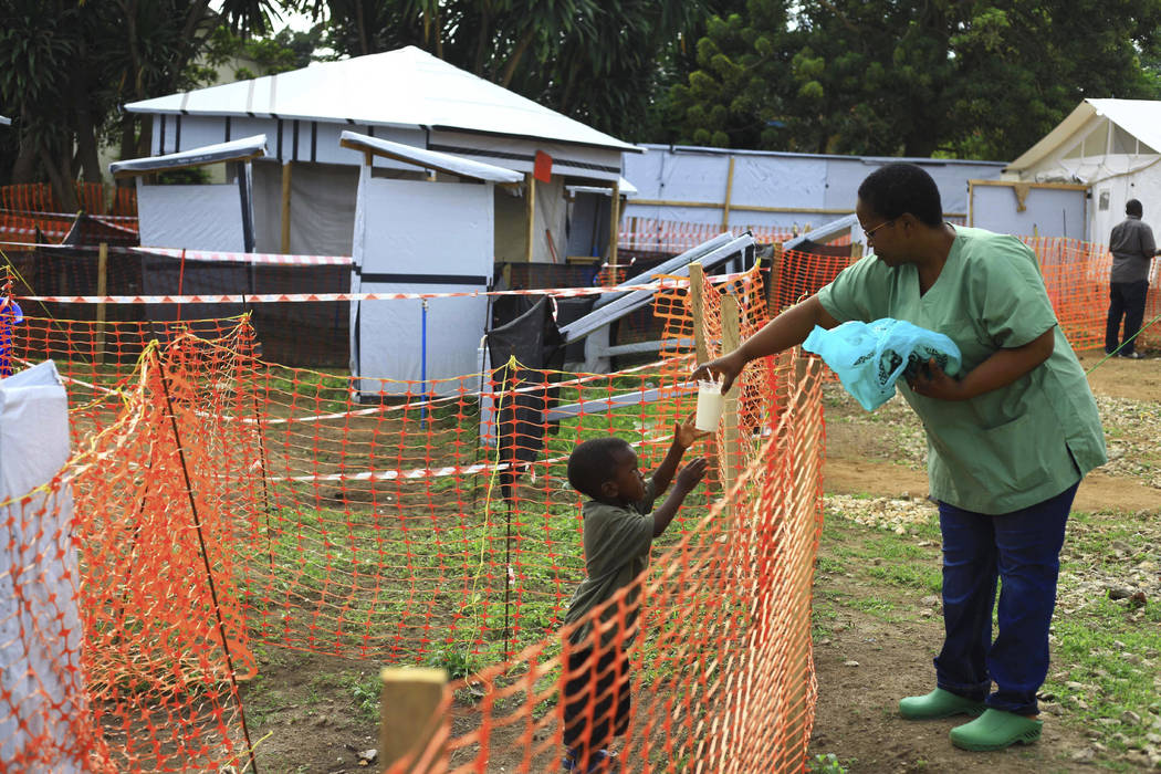 A health worker feeds a boy suspected of having the Ebola virus at an Ebola treatment centre in ...