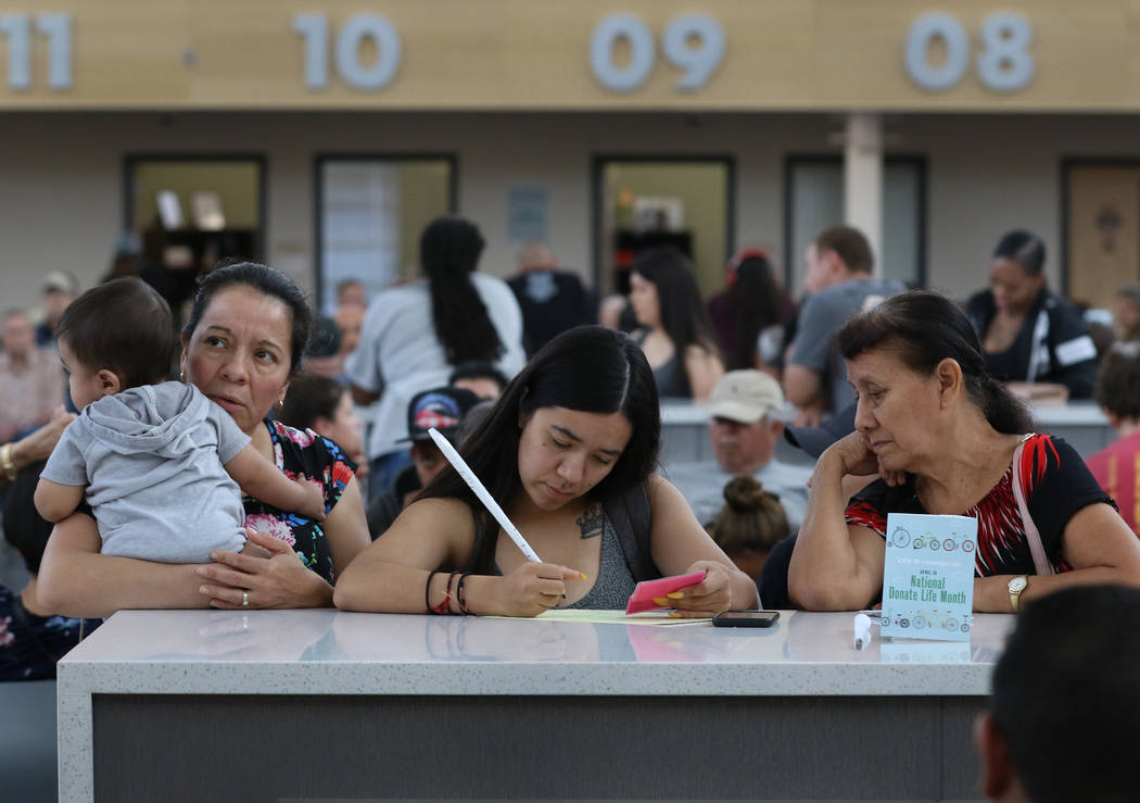 Customers, who declined to give their names, fill out forms at East Sahara DMV office on Friday ...