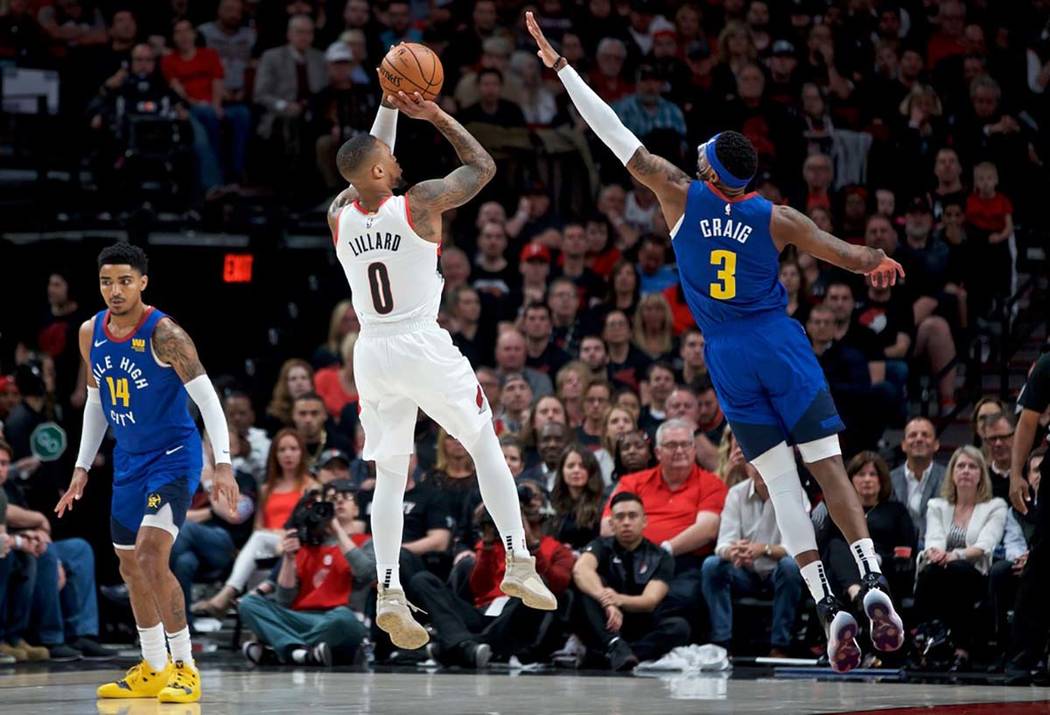 Portland Trail Blazers guard Damian Lillard, center, shoots over Denver Nuggets forward Torrey ...