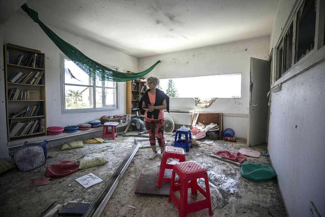 A woman looks at the damage caused by a rocket fired from Gaza that hit a house in a moshav in ...