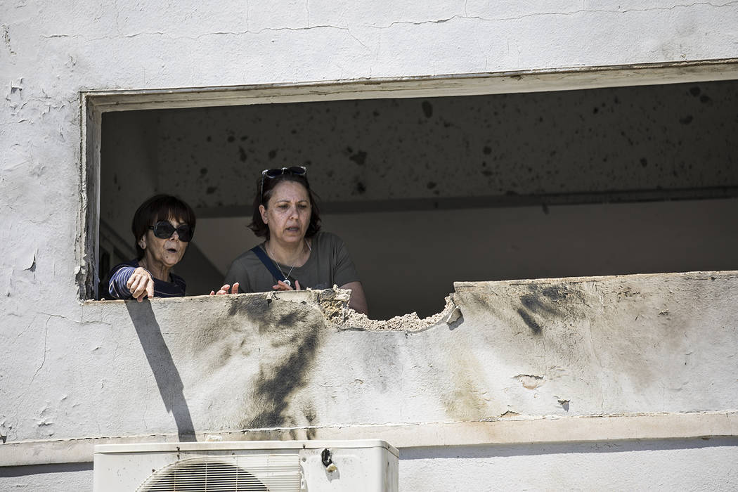 Women look at the damage caused by a rocket fired from Gaza that hit a house in a moshav in Isr ...