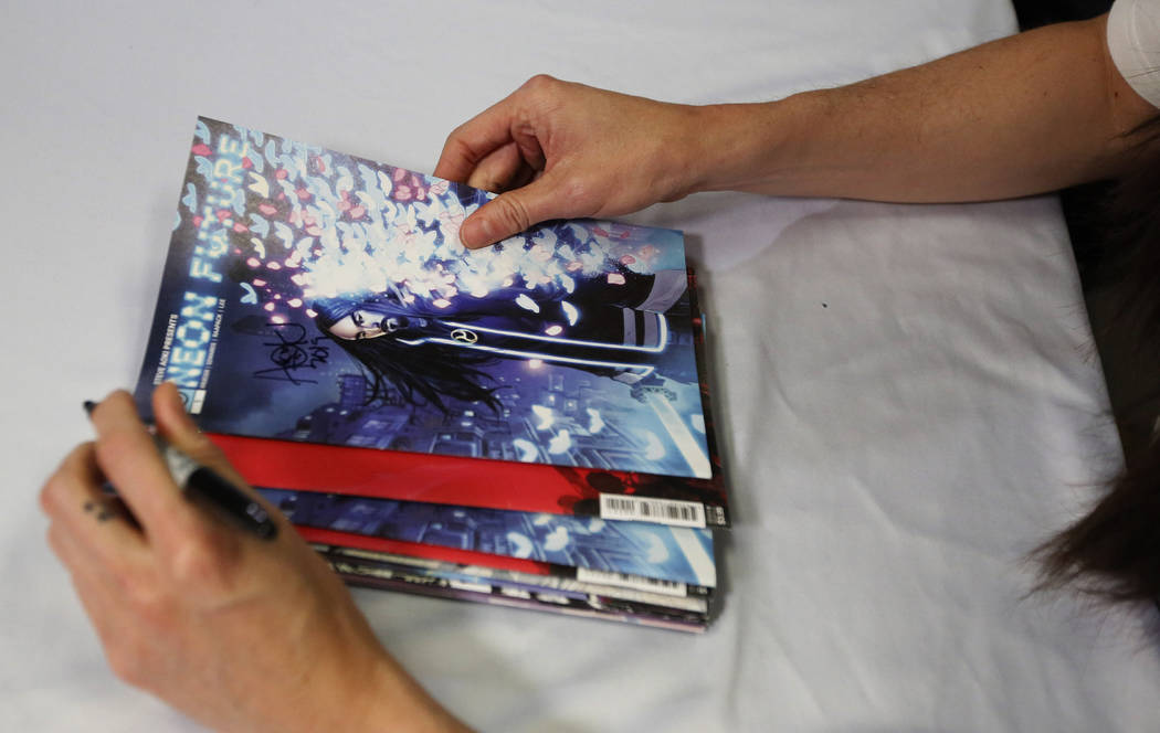 Steve Aoki holds and signs his comic book during a signing of his new "Neon Future" c ...