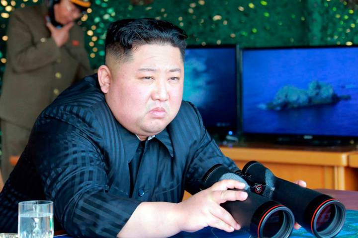 North Korean leader Kim Jong Un, equipped with binoculars, observes tests of different weapons ...