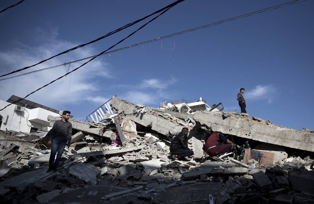 Palestinians check the damage of a multi-story building following Israeli airstrikes in Gaza Ci ...