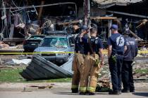 Debris can be seen as emergency personnel and others search and clear the scene of an explosion ...