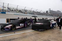 Teams push their cars down pit road after a NASCAR Cup Series auto race was postponed due to in ...