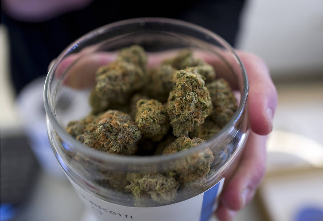 A bud tender shows a top cannabis strain at Serra, a dispensary in Portland, Ore., in February ...