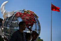 People walk by a globe structure showing the United States of America on display outside a bank ...