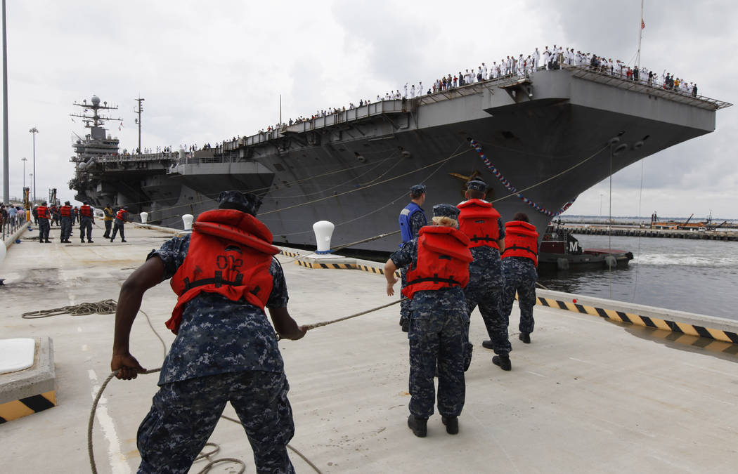 Navy shore crew haul in lines as the nuclear-powered aircraft carrier USS Abraham Lincoln arriv ...
