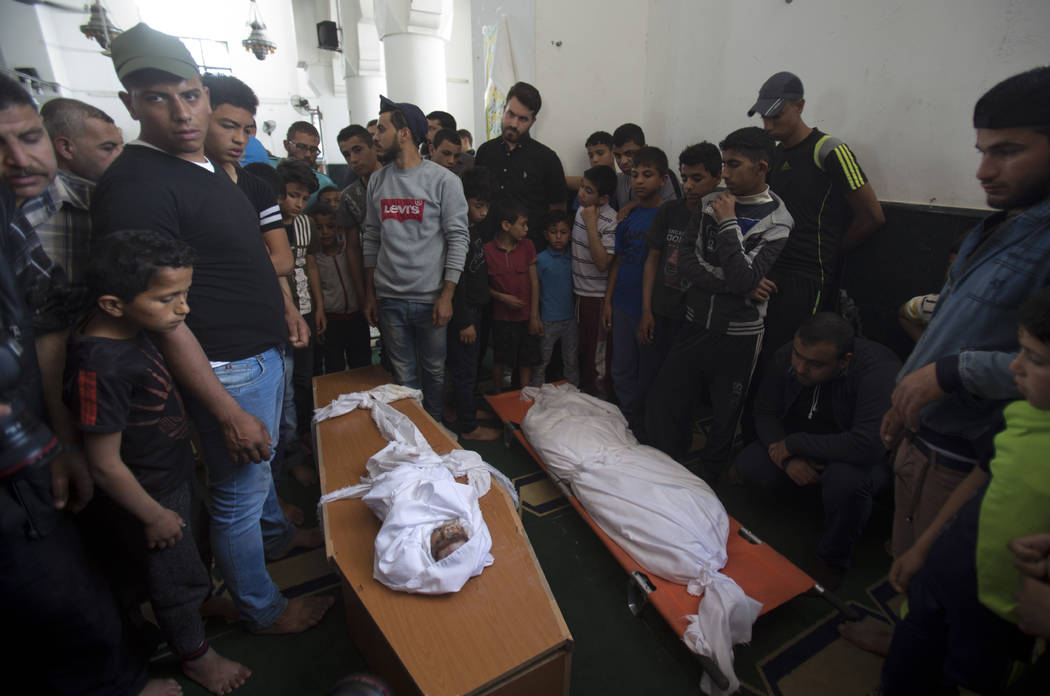 Palestinians stand around the bodies of a four-months-old girl Maria Al-Ghazali, her father Ahm ...