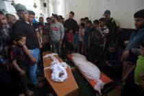 Palestinians stand around the bodies of a four-months-old girl Maria Al-Ghazali, her father Ahm ...
