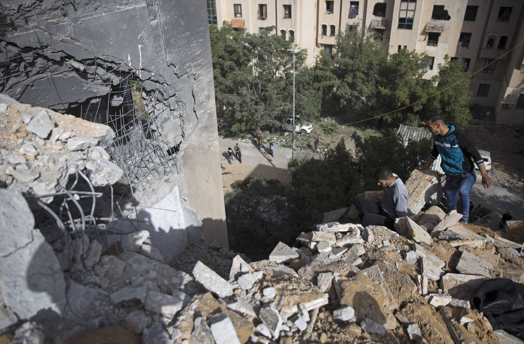 Palestinians inspect the damage of a destroyed house following a late night Israeli missile str ...