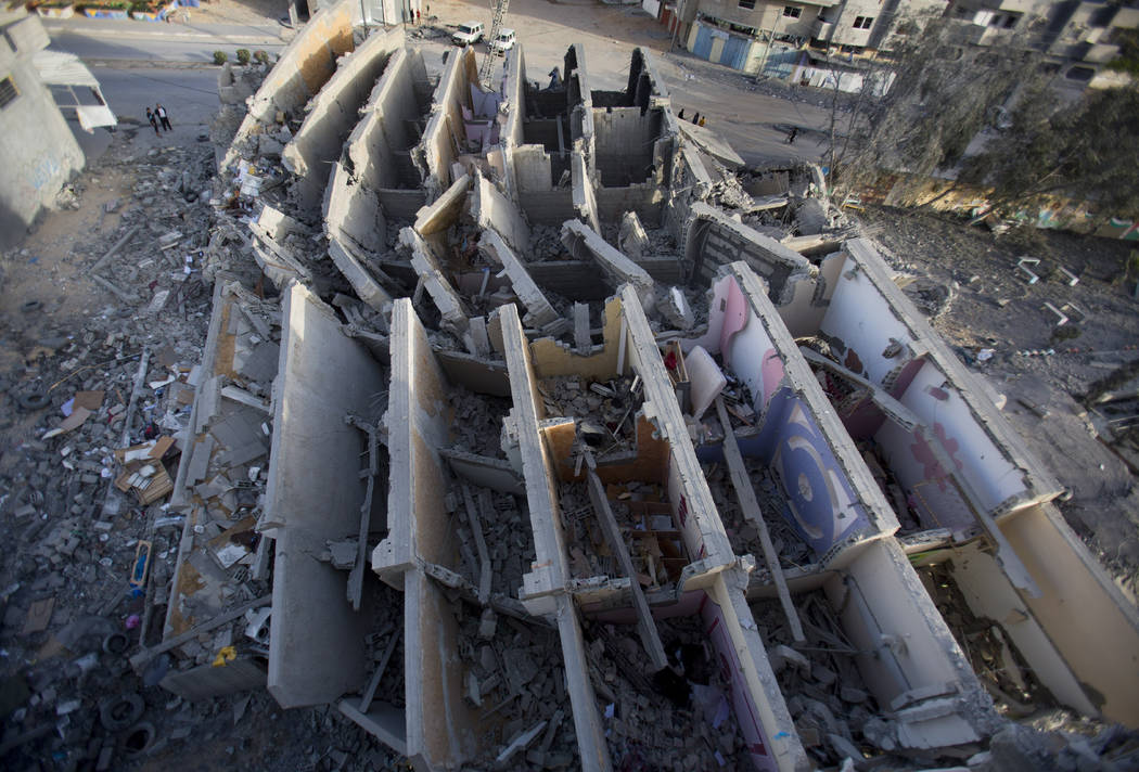 Palestinians check the damage of a destroyed multi-story building was hit and destroyed on Sund ...