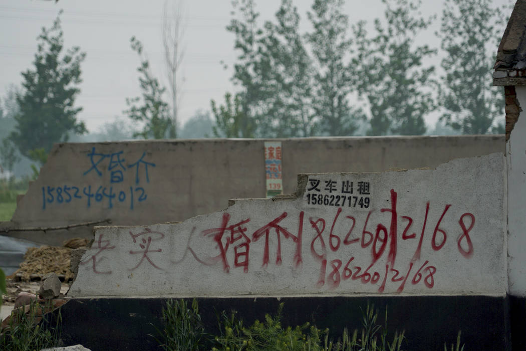In this April 29, 2019 photo, graffiti advertising a marriage agent is spray-painted on the wal ...