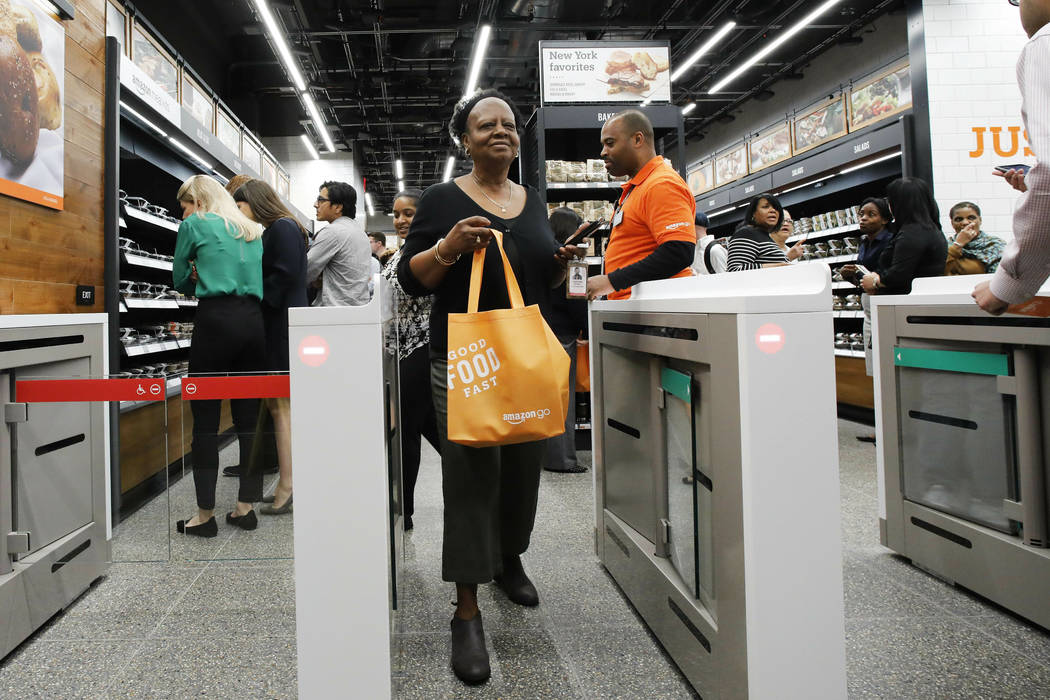 A customer carries her shopping bag as she walks out of a newly-opened Amazon Go store, Tuesday ...