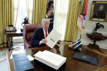 President Donald Trump displays the $1.5 trillion tax overhaul package he had just signed, Frid ...