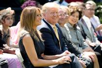 First lady Melania Trump, left, accompanied by President Donald Trump, center, takes a seat dur ...