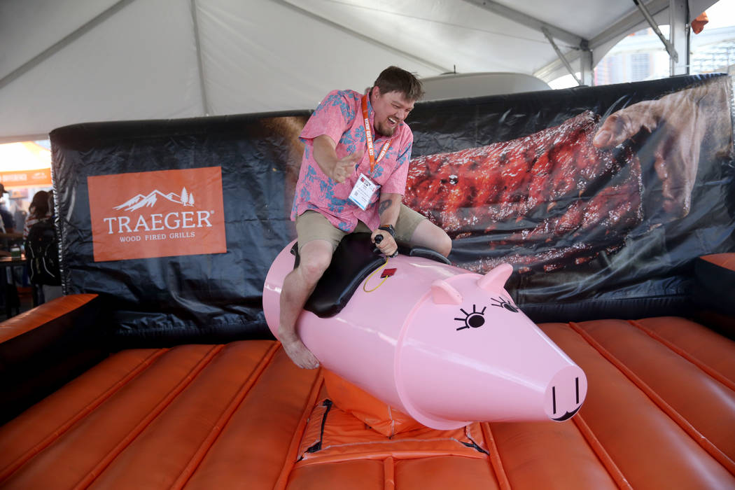 Jared Maclean of Salt Lake City rides the mechanical pig in the Traeger Wood Fired Grills booth ...