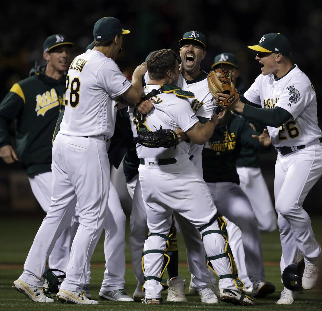 Oakland Athletics' Mike Fiers, center, celebrates with Matt Olson (28) Chad Pinder (18) and Mat ...