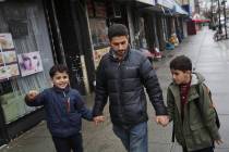 Sadek Ahmed walks with his sons Adel, 9, right, and Mutaz, 7, after picking them up from school ...