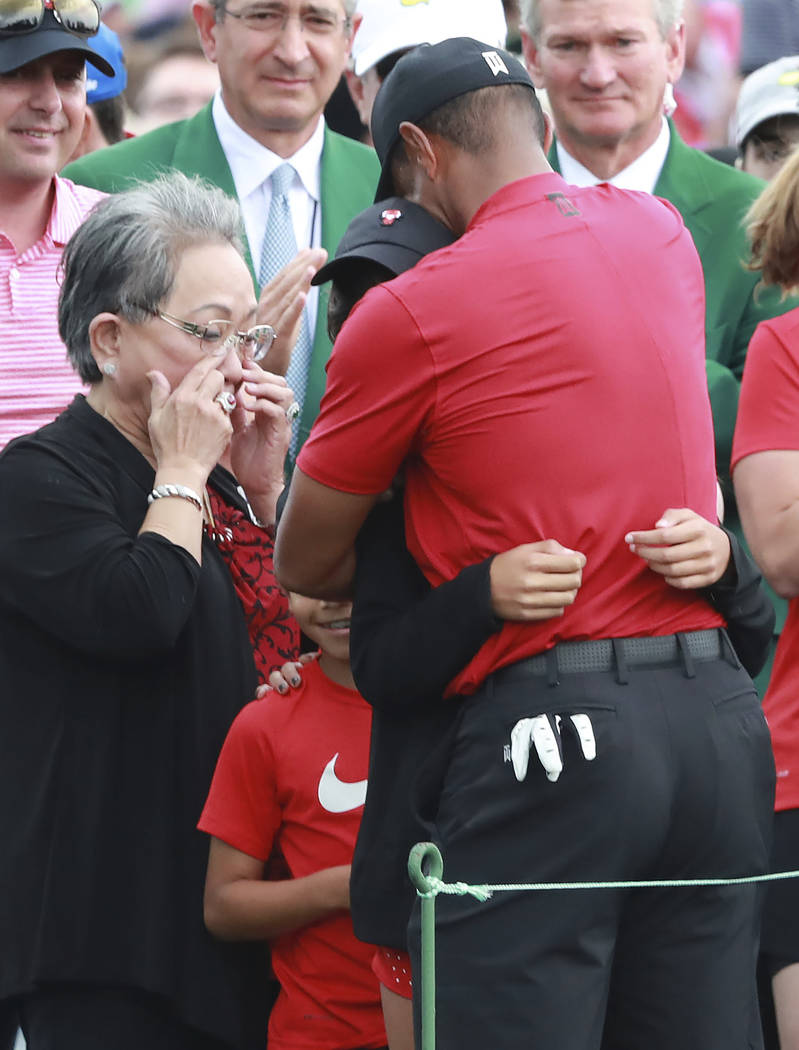 Tiger Woods' mother Kultida Woods wipes away tears as he hugs his daughter Sam and son Charlie ...