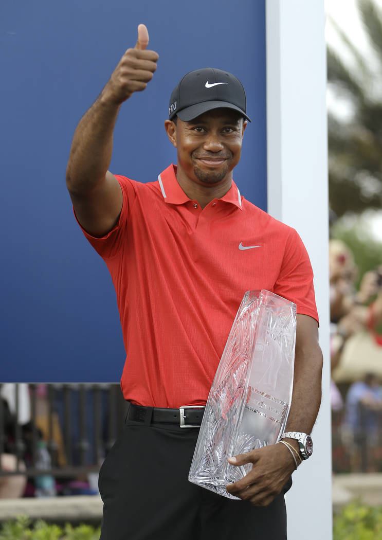 FILE - In this May 12, 2013, file photo, Tiger Woods gives a thumbs-up as he holds the trophy a ...