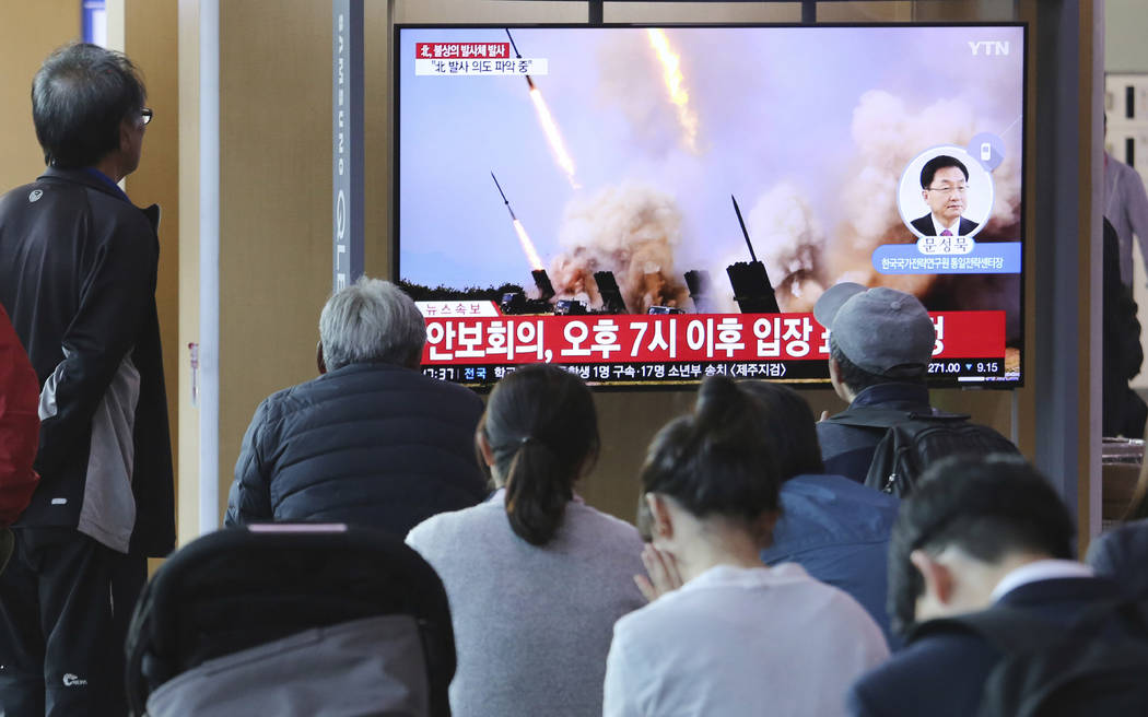People watch a TV showing a file photo of North Korea's weapon systems during a news program at ...