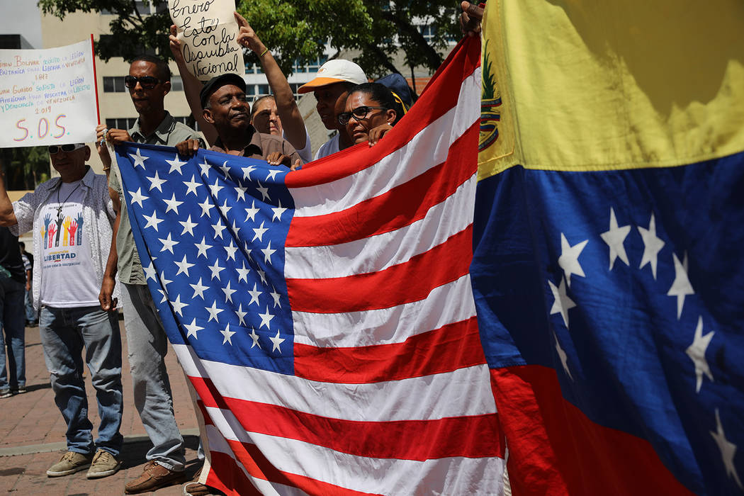 Opponents of the Nicolas Maduro government hold national flags representing the U.S, and Venezu ...