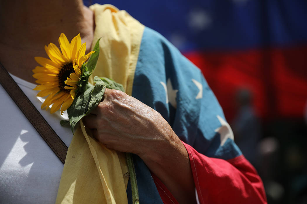 An opponent of the Nicolas Maduro government holds a sunflower and a Venezuelan national flag a ...