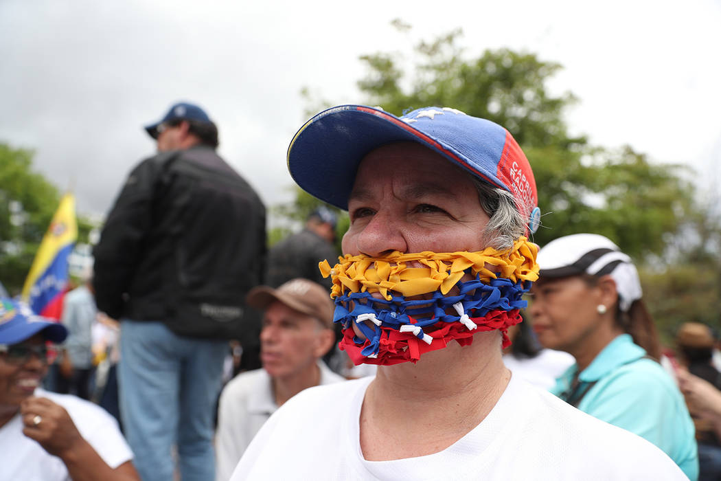 An opponent of the Nicolas Maduro government, his mouth covered with strands representing the n ...