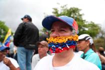 An opponent of the Nicolas Maduro government, his mouth covered with strands representing the n ...